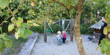 Pige hjælper dreng med at gynge