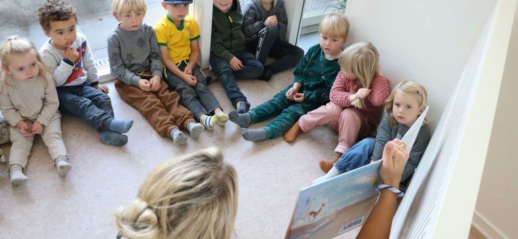 Børn får læst højt af bog i rundkreds