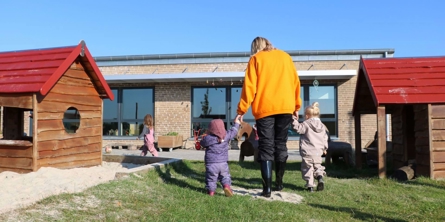 Pædagog går med et vuggestuebarn i hver hånd