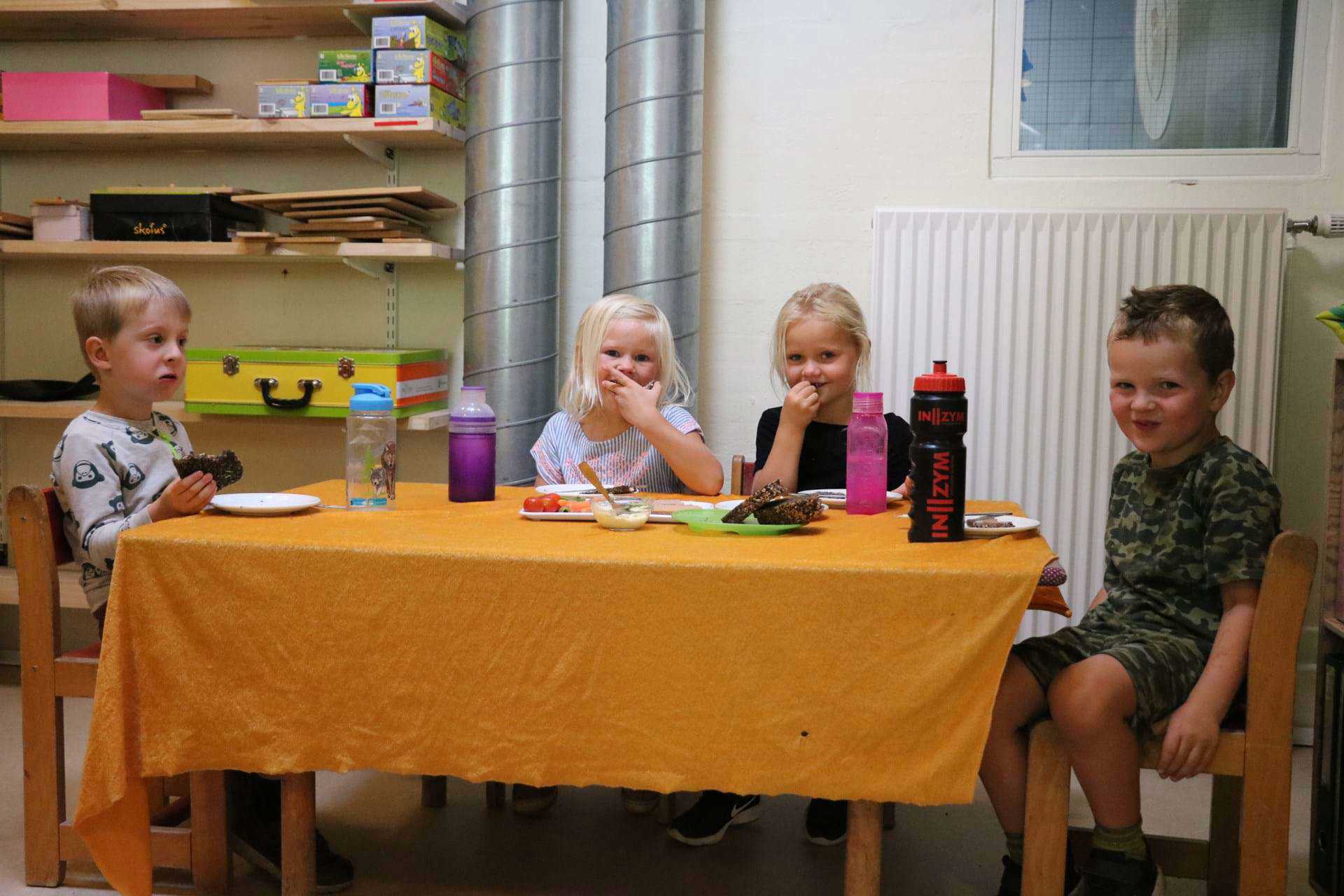 Børnehavebørn spiser frokost og griner