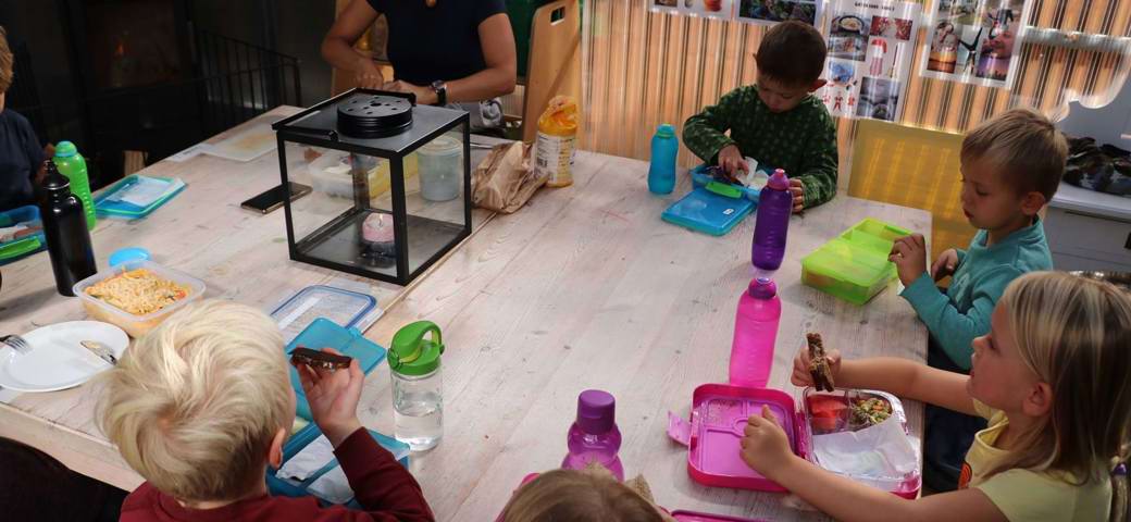 Børnehavebørn spiser madpakker i udeværksted
