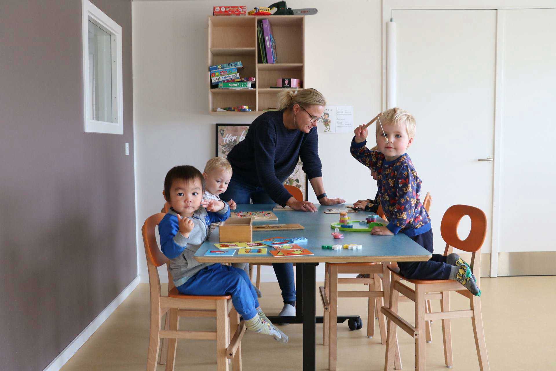 Vuggestuebørn laver puslespil omkring bord