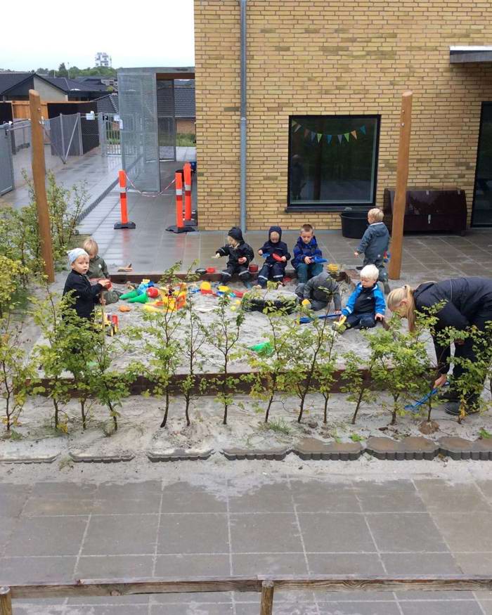 Børn leger i sandkasse i regnvejr