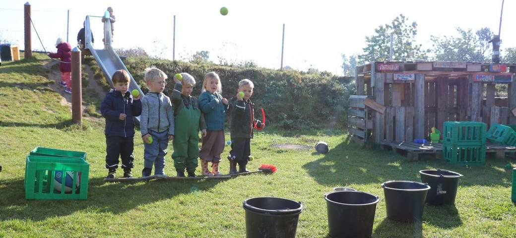 Fem børn kaster bolde i spande