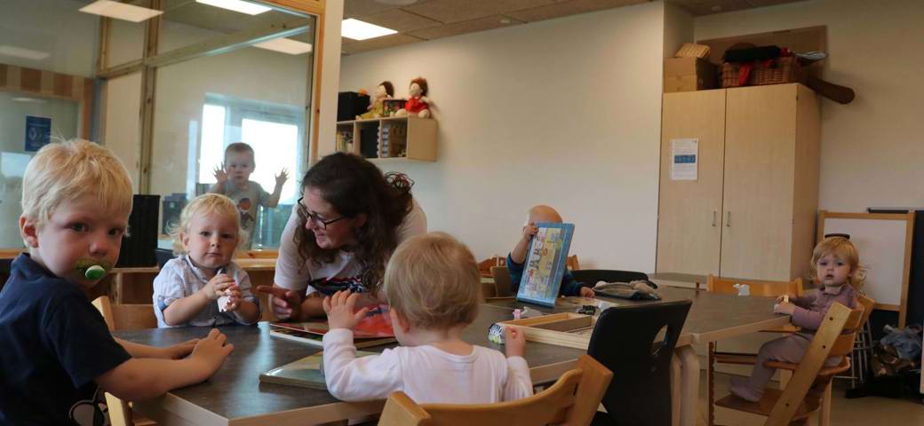 Dagplejebørn og dagplejer laver puslespil omkring et bord