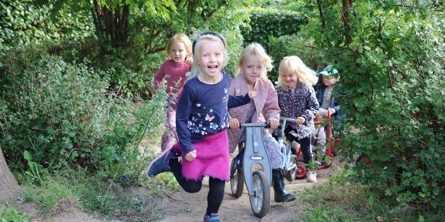Fem børn løber og cykler ud fra krat