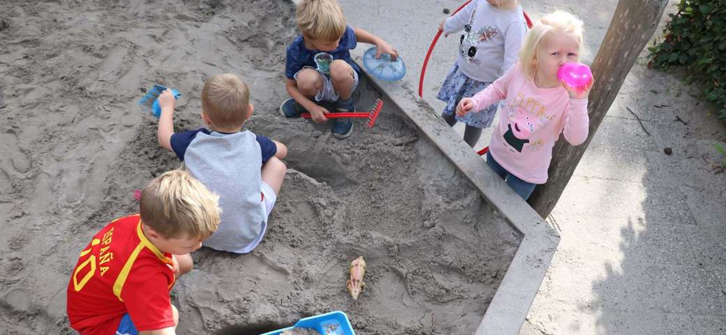 Børn leger i sandkasse set fra oven
