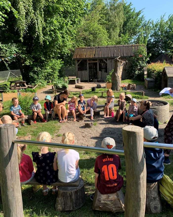 Børn og pædagoger holder samling på legeplads