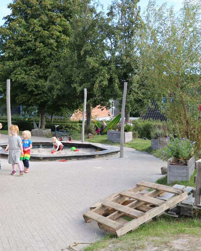 Børn og voksen i leg nær sandkasse