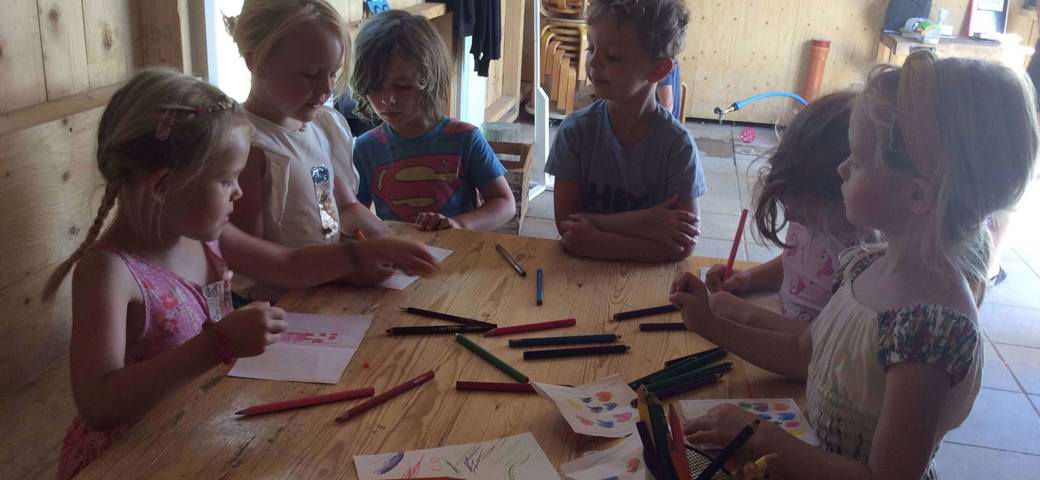 Børn tegner omkring bord i udeværksted