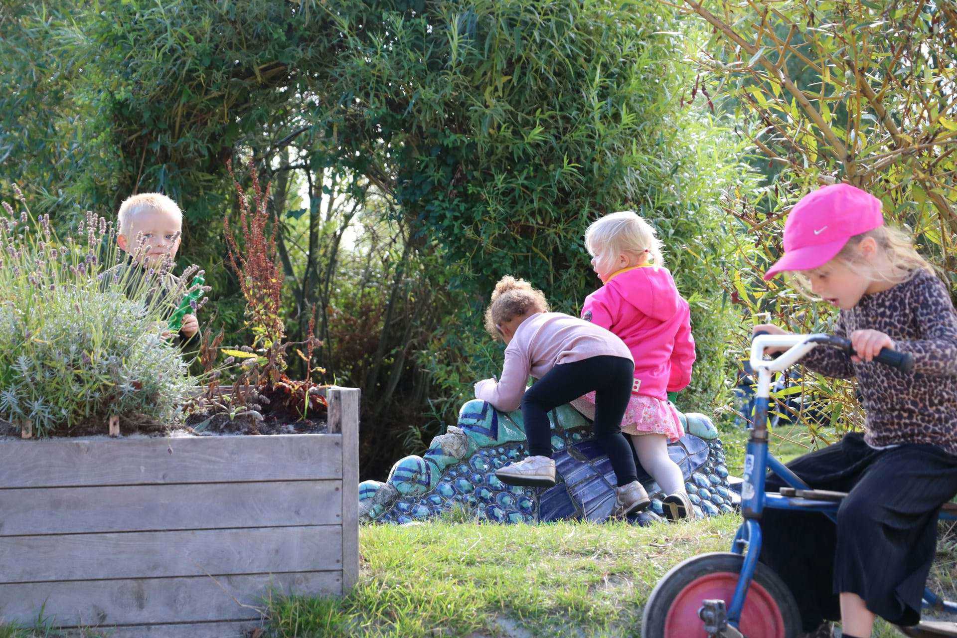 Fire børn leger med cykel og skulptur