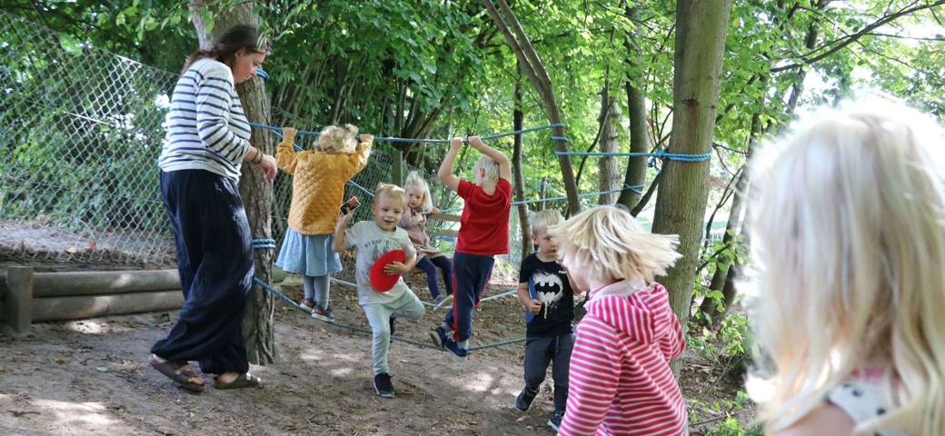 Børn leger på reb blandt træer