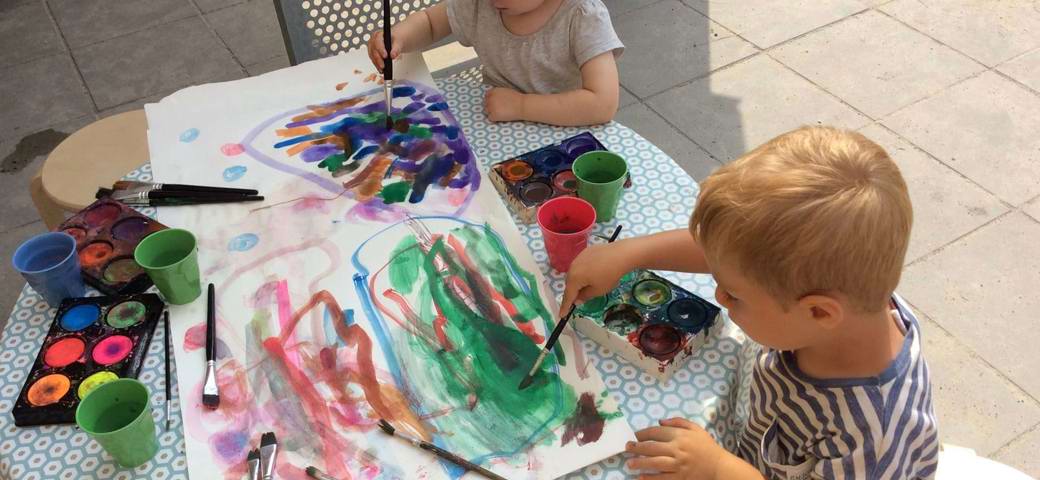 To børn maler med vandfarve i skyggen
